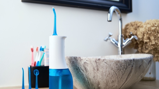 Photo of a bathroom counter with a blue water pick front and center.